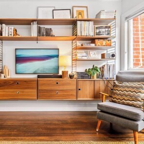 LIVING: The living room features a stylish mid century wall unit  with a collection of books and treasured objects. The Smart TV has Netflix, Binge and Amazon Prime. 