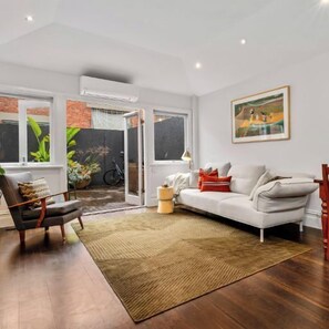 LIVING: The spacious living room has a large comfortable couch with large screen Smart TV, Sonos sound system and air conditioning. The stylish wall unit has a large collection of books and collectibles to delight the visitor.