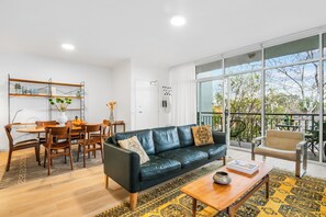 LOUNGE:  The large sunny open plan lounge looks out over balcony and trees with the streetscape below. 