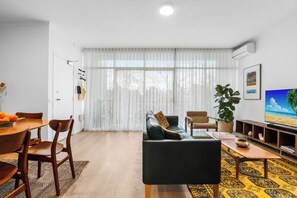 LIVING ROOM: The Living Room opens out on to the large balcony that is a second living space. The apartment features a collection of original Mid Century furniture. The curtain add a cozy feel and privacy. 