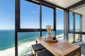 Enclosed balcony with a high table and chairs, perfect for morning coffee, offering a stunning view of the southern coastline and potential whale sightings.
