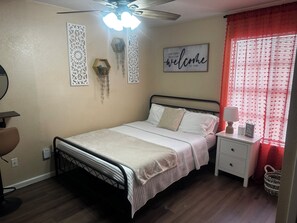 Bedroom with queen bed and extra pillows and blanket.