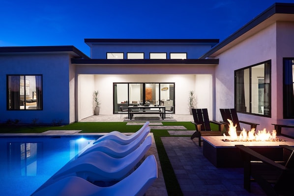 Unit 2: Resort-like backyard with a covered patio offering outdoor dining with seating for 8 guests, a sparkling blue heated pool with sun loungers, BBQ grill and a fire pit.