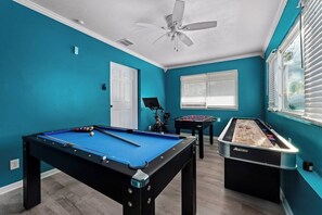 Gameroom featuring a mid-size pool table, foosball, shuffleboard, 75-inch TV, and a Peloton bike for fun and fitness.