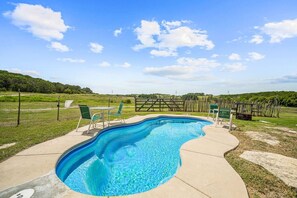 Enjoy a refreshing swim while taking in the beautiful view of the expansive property. The poolside area offers a peaceful and scenic environment for guests to relax and enjoy the outdoors.