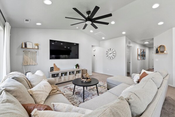 An oversized comfy sectional sofa surrounding a massive 85" smart TV.