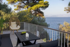 Sea-view balcony nestled in trees with cozy outdoor seating

