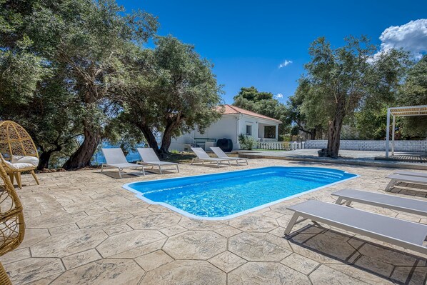 Pool, garden, and sea views with a glimpse of the villa’s beautiful exterior