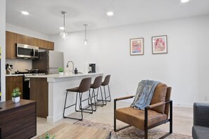 Prepare meals in this modern, fully-equipped kitchen featuring stainless steel appliances and a spacious island with bar seating. The open layout makes it easy to cook and entertain, ensuring a delightful culinary experience during your stay.