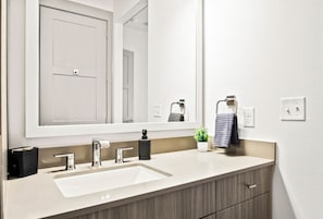 This bright and welcoming bathroom invites you to freshen up in comfort. Enjoy the forest-inspired shower curtain that adds a calming touch to your routine, complemented by the cozy rug underfoot and sparkling clean fixtures.