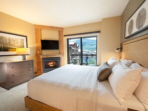 Warm bedroom with a queen bed and a charming fireplace.