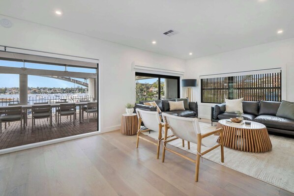 Enjoy the ultimate relaxation in a lounge complete with a comfortable couch, stylish table, and TV, all opening up to a balcony with stunning water views