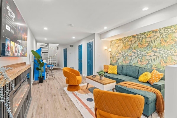 Immerse yourself in comfort and style in this chic living area with vibrant accents. You will love the cozy seating, inviting wallpaper, and modern entertainment setup, perfect for unwinding after a day of exploring!