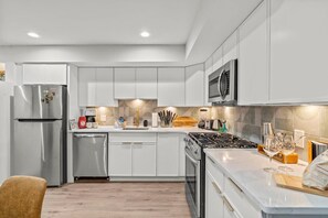 Step into a sleek, modern kitchen featuring elegant gold accents, high-end stainless steel appliances, and ample counter space. Perfect for culinary adventures and creating memorable meals during your stay!