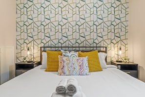 The master bedroom is a blend of comfort and style with its geometric accent wall and cozy furnishings. You will love the thoughtful touches and vibrant decor, making it a perfect retreat for relaxation.
