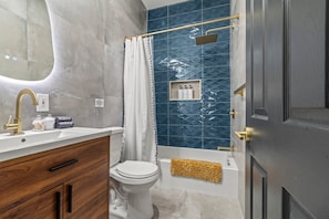 Indulge in the luxurious bathroom with modern fixtures and stylish blue tiles. You will love the spa-like atmosphere, complete with a rainfall showerhead and elegant gold accents, perfect for unwinding after a day of exploring.