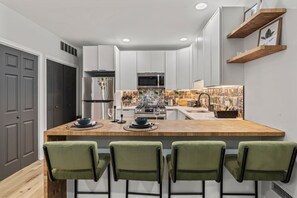 You will love cooking in this sleek, modern kitchen with a spacious island for dining. The chic bar stools and stylish backsplash add a touch of elegance to your culinary experience.
