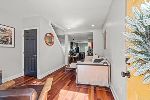 Step into this inviting living space, where sunlight dances on gleaming hardwood floors and modern decor welcomes you warmly, flowing effortlessly from the cozy seating area to the sleek dining space.