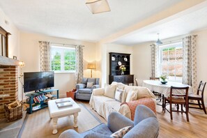 Relax in the inviting living room at Moat Cottage, with comfy sofas, armchairs, and a dining table – the perfect self-catering stay in North Yorkshire.