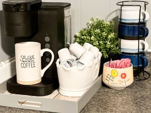 The coffee station is thoughtfully equipped with a variety of in-house consumables, including a selection of ground coffee, sweeteners, and creamers to suit every taste.