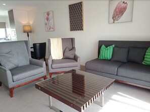 Our spacious lounge room boasts a chic grey couch in a stylish setting, with plenty of room to stretch out, relax, or gather with friends.