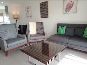 Our spacious lounge room boasts a chic grey couch in a stylish setting, with plenty of room to stretch out, relax, or gather with friends.