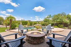 Beautiful backyard with a covered patio, sparkling pool, shaded seating, dining area, grill, and grass area.