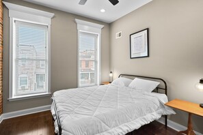The second bedroom features queen bed, desk, & luggage rack. Large windows. 