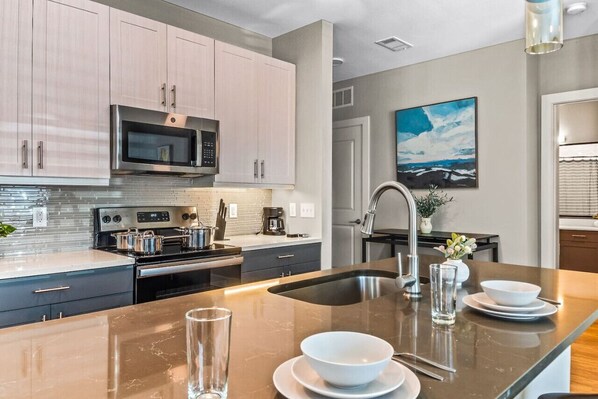 Prepare meals in this modern, fully-equipped kitchen featuring stainless steel appliances and a spacious island with bar seating. The open layout makes it easy to cook and entertain, ensuring a delightful culinary experience during your stay.