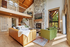 This light-filled living room features soaring ceilings and stunning fireplace 