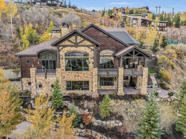 A view of the front of Morning Star, a home in Deer Valley. The outside has wood shingles and stone siding, you can see the top deck with views inside