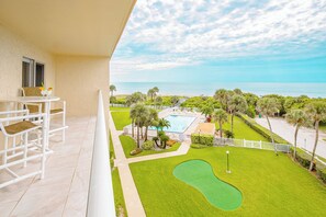 Large patio with outdoor seating overlooking the lush landscaping and mini-golf area.