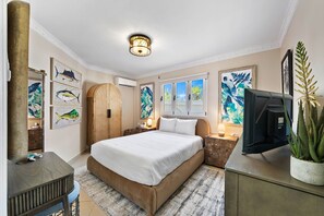 - Cozy bedroom with a plush queen-size bed and calming coastal-themed artwork - Natural light filters through windows, highlighting the earthy tones - Thoughtful details like a wooden wardrobe and decorative plants enhance the room's serene vibe
