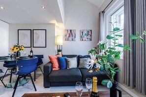 The open-plan living room and dining area benefit from a 50-inch Smart TV, a 4-seater dining table,  a 3-seater breakfast bar, plenty of space to sit down in the evenings and a double sofa bed.
