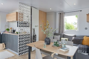Unwind in the bright and cosy living area of your mobile home, featuring a comfortable sofa, dining space, and large windows that fill the room with natural light.