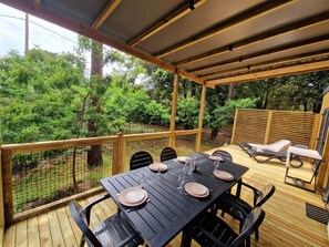 Relax on the covered patio with a plancha grill, perfect for alfresco dining. The spacious table comfortably seats six, surrounded by nature for a serene outdoor experience.