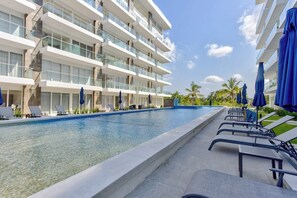 Shaded lounge chairs around the ground-level pool