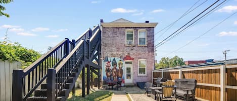 Chill out in the backyard with a vibrant wall mural and a fire pit, perfect for cozy, relaxed evenings.