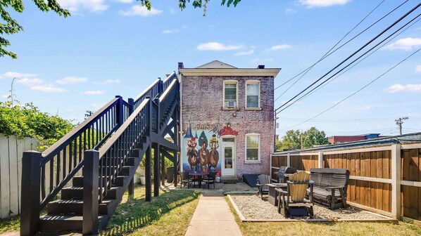 Chill out in the backyard with a vibrant wall mural and a fire pit, perfect for cozy, relaxed evenings.