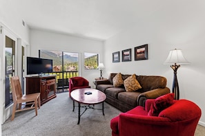 Living area with flat screen TV, queen size sleeper sofa, wood-burning fireplace, and access to the private balcony.