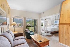 Living room featuring a queen sized sleeper sofa, flat screen TV, and balcony access to incredible mountain views.