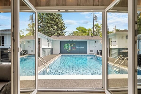 Relax in luxury at "The Experience YYC" with a private, sparkling pool viewed from cozy indoor seating. The tropical-inspired setting is perfect for morning swims or evening dips, ideal for families, couples or groups in Calgary.