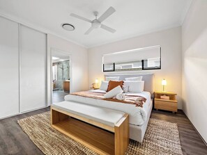 Your private sanctuary awaits—this beautifully styled first bedroom includes a plush queen bed, ceiling fan, and direct access to a luxurious ensuite.