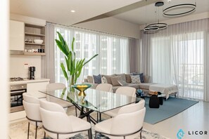 Spacious open-plan living room and dining area with floor-to-ceiling windows offering stunning city views.