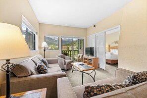 Living area with large mounted flat screen TV, queen size sleeper sofa, wood-burning fireplace, and access to the private balcony.