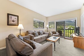 Living area with large mounted flat screen TV, queen size sleeper sofa, wood-burning fireplace, and access to the private balcony.