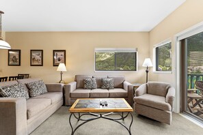 Living area with large mounted flat screen TV, queen size sleeper sofa, wood-burning fireplace, and access to the private balcony.
