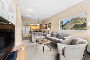 Living area with large mounted flat screen TV, queen size sleeper sofa, wood-burning fireplace, and access to the private balcony.