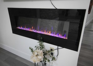 The living room's modern decor and electric fireplace create a warm and inviting atmosphere.
