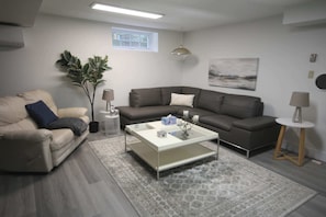 Relax in the cozy living room with a snug L-shaped sofa and a 55" Smart TV.